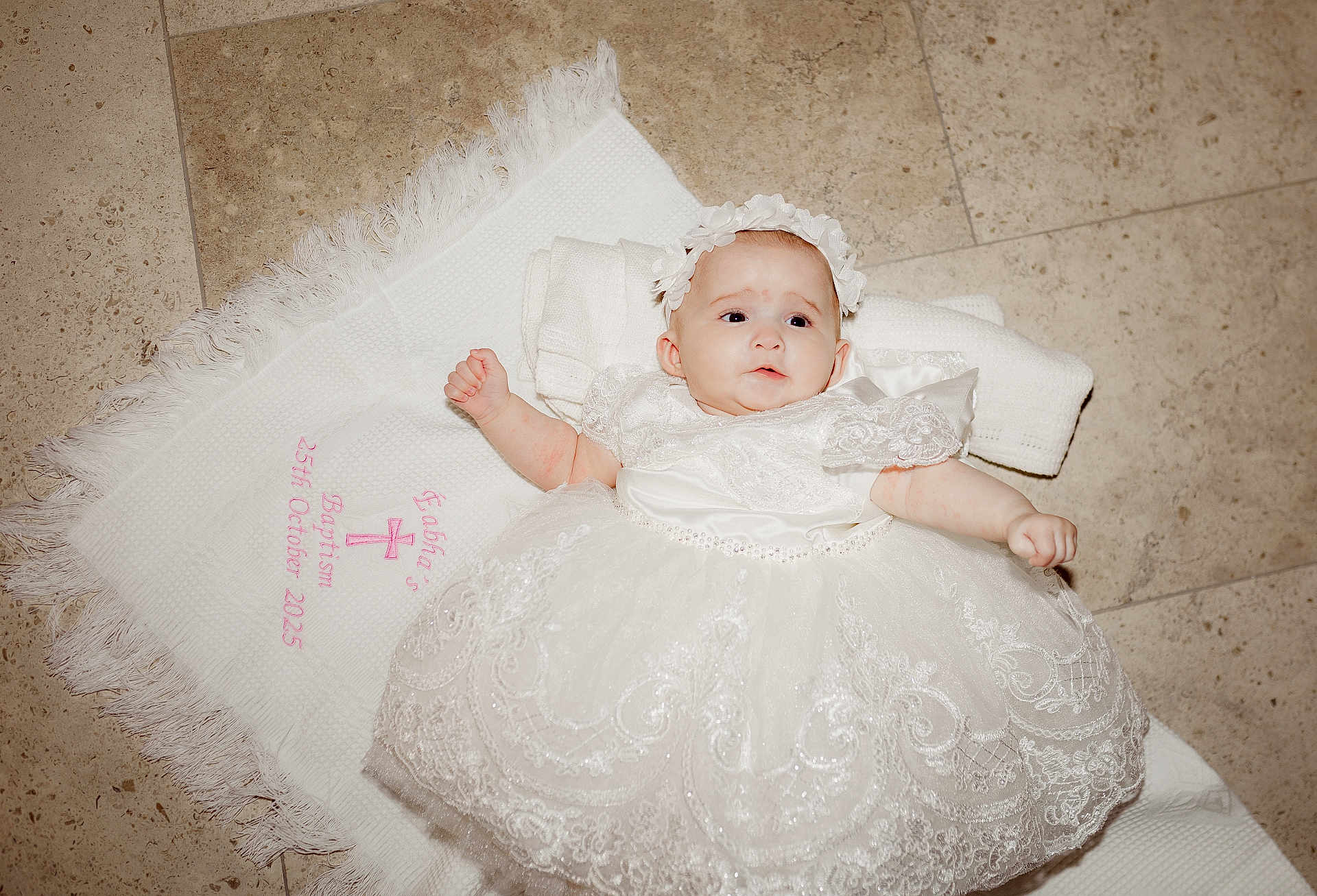 éabha is registered to the contest to win money with this photo: baby, infant, dress, white_dress, lace, headband, floor, tiled_floor, cloth, embroidery, baptism, celebration, cute, child, portrait, laying_down, indoors, person, newborn, ceremony