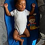baby, sleeping, blue_cushion, white_onesie, doll, playpen, infant, child, indoors, resting, cute, peaceful, toy, soft_light, skin, curly_hair, relaxing, toddler, nap, comfort
