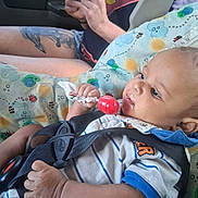 Kaysan joined the competition — help win amazing prizes! baby, infant, car_seat, lollipop, red_lollipop, vehicle, car_interior, adult, tattoo, hands, clothing, striped_shirt, blanket, patterned_fabric, seat_belt, portrait, close_up, sitting, alert, family