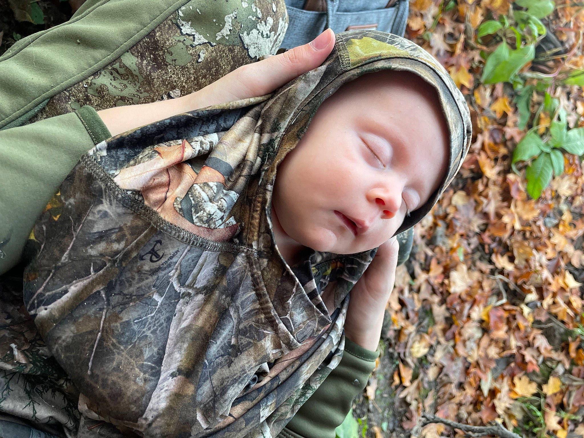 Dahlia is registered to the contest to win money with this photo: cap, child, eyewear, fashion_accessory, grass, happy, headwear, hood, hoodie, knit_cap, military_camouflage, pattern, people_in_nature, person, plant, portrait_photography, sitting, soil, sun_hat, toddler