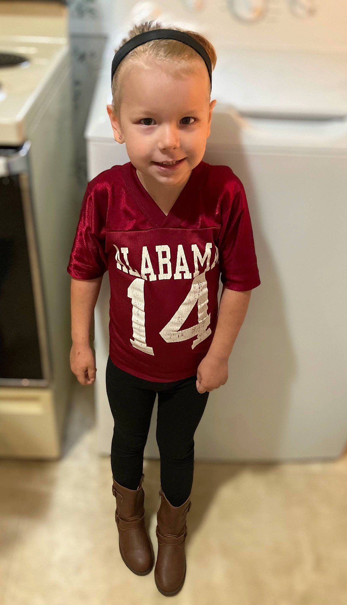 Rosemarie is registered to the contest to win money with this photo: baby_toddler_clothing, child, eye, fashion_design, flooring, fun, hairstyle, happy, human_leg, jersey, joy, knee, person, room, skin, sleeve, sportswear, standing, t_shirt, thigh