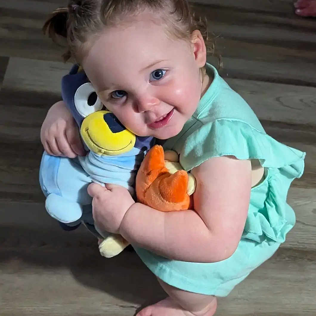 Ava is registered to the contest to win money with this photo: baby, barefoot, blue_eyes, child, cuddling, cute, floor, green_dress, happy, indoor, person, pigtails, playful, plush_toys, skin, smiling, squatting, stuffed_animals, toddler, young_child