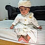 baby, barefoot, bed, child, couch, cute, floor, furniture, indoor, indoors, person, portrait, serious_expression, sitting, traditional_clothing, turban, white_outfit, wooden_floor, young, young_child