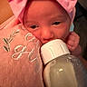 baby, infant, bottle, feeding, pink_bow, headband, blanket, embroidery, close_up, face, sleepy, cute, newborn, hand, soft_texture, milk, child, indoors, portrait, cozy