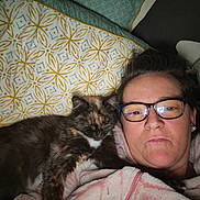 Poupouille a rejoint le concours — aidez-le/la à gagner de superbes lots ! person, cat, glasses, bed, blanket, fleece_jacket, tortoiseshell_cat, sleeping_cat, indoor, close_up, cuddling, resting, comfortable, portrait, eyewear, home, relaxation, animal, pet, companion