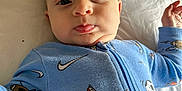 Oakley joined the competition — help win amazing prizes! baby, infant, face, blue_onesie, sports_pattern, nike_logo, lying_down, white_sheet, close_up, child, young, cute, apparel, sleepwear, person, portrait, expression, indoors, soft_lighting, skin