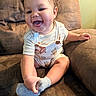 Giovanni is registered to the contest to win money with this photo: baby, child, couch, crossed_legs, curly_hair, face, happy, indoors, infant, lifestyle, living_room, overalls, photography, portrait, sitting, smiling, socks, sofa, striped_shirt, warm_lighting