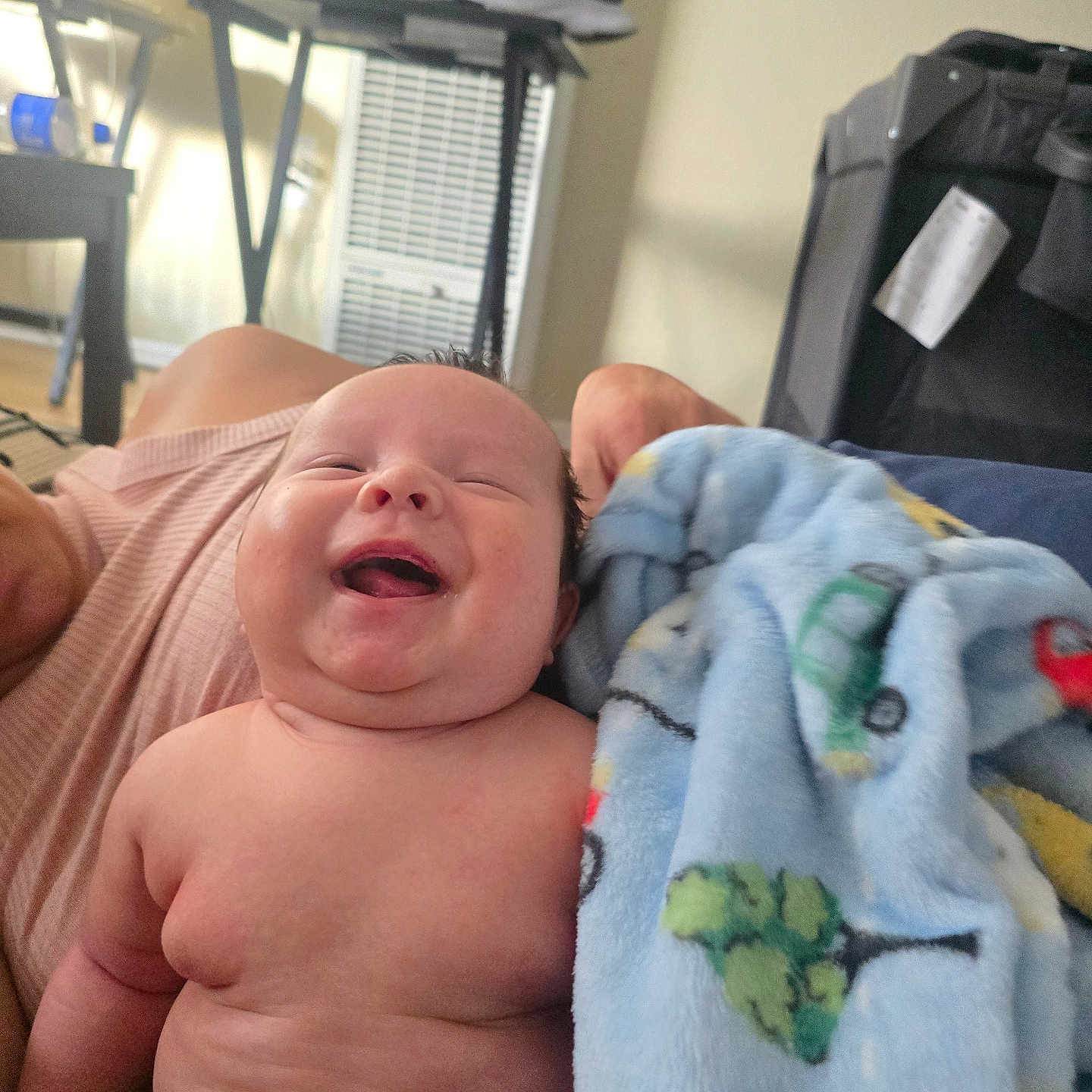 Iitanon is registered to the contest to win money with this photo: baby, blanket, blue_blanket, child, cute, diaper, face, furniture, happy, indoor, infant, laughing, light, patterned_blanket, person, shoe, skin, smiling, table, window_blind