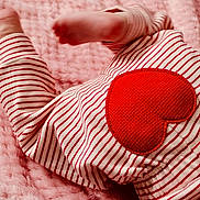 James joined the competition — help win amazing prizes! baby, feet, pajamas, striped_clothing, red_heart, pink_blanket, soft_texture, infant, close_up, sleepwear, cute, cozy, child, newborn, foot, fabric, pattern, warm, resting, bed