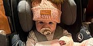 Sutton is registered to the contest to win money with this photo: baby, car_seat, pacifier, pink_blanket, pink_hat, pom_poms, infant, child, clothing, warm, cozy, cute, indoors, seat_belt, portrait, face, hand, newborn, baby_clothes, soft
