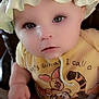 Isabella is registered to the contest to win money with this photo: baby, child, hat, yellow_shirt, cartoon_characters, close_up, face, eyes, curious, soft_lighting, infant, cute, portrait, indoors, skin, hands, clothing, expression, headwear, young