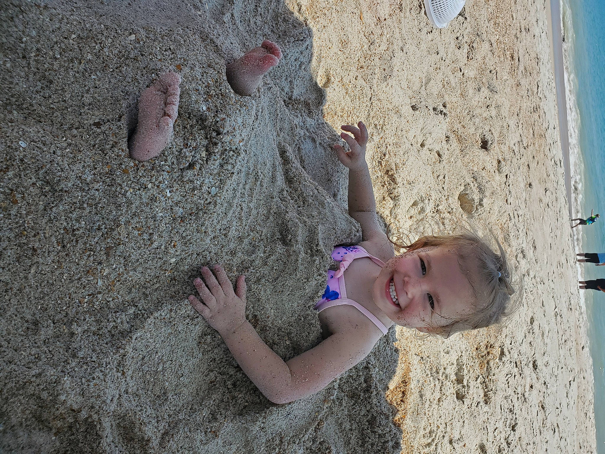 Mckenna joined the competition — help win amazing prizes! arm, beach, child, facial_expression, foot, fun, happy, head, human_body, human_leg, joy, leisure, people_in_nature, person, plant, rock, sand, shadow, skin, toddler