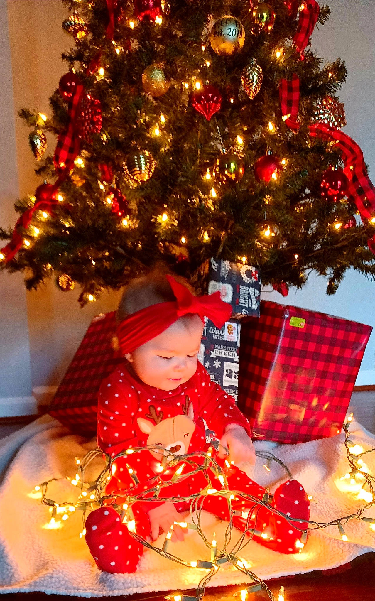 Mckenna joined the competition — help win amazing prizes! baby, baby_toddler_clothing, christmas, christmas_decoration, christmas_eve, christmas_ornament, christmas_tree, conifer, decoration, event, evergreen, headwear, holiday, holiday_ornament, light, ornament, person, red, toddler, tradition