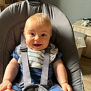 Noah a rejoint le concours — aidez-le/la à gagner de superbes lots ! baby, baby_seat, bib, blue_clothing, cabinet, child, comfort, cute, face, furniture, happy, indoor, infant, light, person, sitting, smile, straps, wooden_floor, young