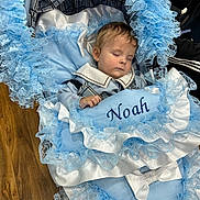 Noah is registered to the contest to win money with this photo: baby, sleeping, stroller, blue, lace, blanket, white, bow, wooden_floor, face, child, clothing, infant, person, cute, resting, indoors, decorative, soft, peaceful