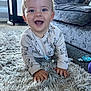 baby, crawling, smiling, indoor, rug, carpet, onesie, clothing, sofa, toy, pacifier, living_room, child, happy, cute, face, hands, floor, plush, infant