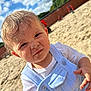 Noah is registered to the contest to win money with this photo: toddler, child, sand, sandbox, outdoor, daylight, blue_sky, clouds, playground, clothing, face, hand, curious, sandy_face, short_hair, white_shirt, overalls, sunlight, smile, young_child