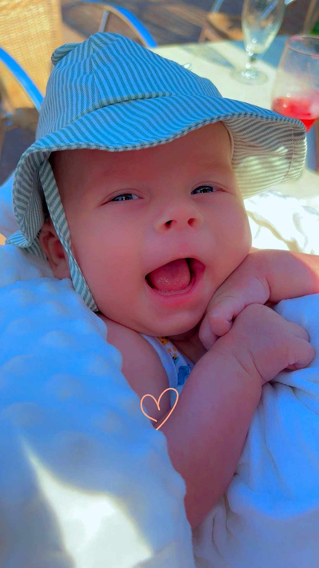 Ulysse a rejoint le concours — aidez-le/la à gagner de superbes lots ! baby, smiling, hat, striped_hat, blanket, outdoor, sunlight, happy, infant, face, closeup, cute, child, wrapped, fist, warm, daylight, portrait, headwear, relaxed