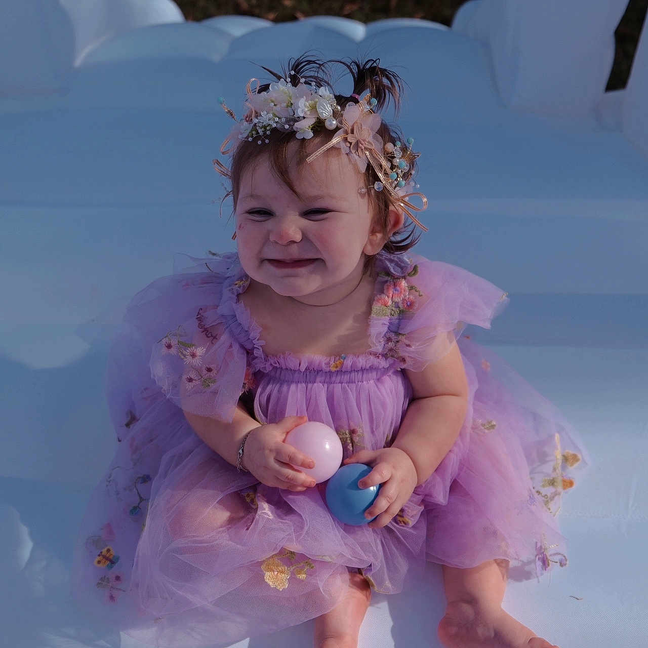 Layley is registered to the contest to win money with this photo: baby, ball, casual, child, colorful, cute, flower_crown, fun, happy, headband, inflatable, outdoor, person, playful, portrait, purple_dress, sitting, smiling, toddler, young_child
