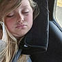 child, sleeping, car, seatbelt, neck_pillow, window, blonde_hair, face, person, portrait, resting, closed_eyes, casual_clothing, interior, travel, seat, young, relaxed, comfort, daylight