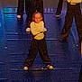 child, children, dance, dancer, performance, stage, costume, yellow_top, black_pants, crossed_arms, group, indoor, lighting, colorful_lights, footwear, young, posing, expression, floor, event