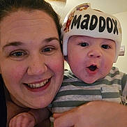 Maddox joined the competition — help win amazing prizes! baby, woman, face, helmet, smile, indoor, child, person, striped_clothing, hand, expression, closeup, parent, infant, protection, headgear, cute, happy, family, love