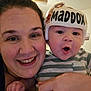 baby, woman, face, helmet, smile, indoor, child, person, striped_clothing, hand, expression, closeup, parent, infant, protection, headgear, cute, happy, family, love