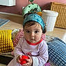 baby, child, indoor, headband, toy, pillow, colorful, curious, sitting, floor, blanket, wicker_basket, plant, red_toy, blue_headband, pink_outfit, home, playtime, cute, portrait