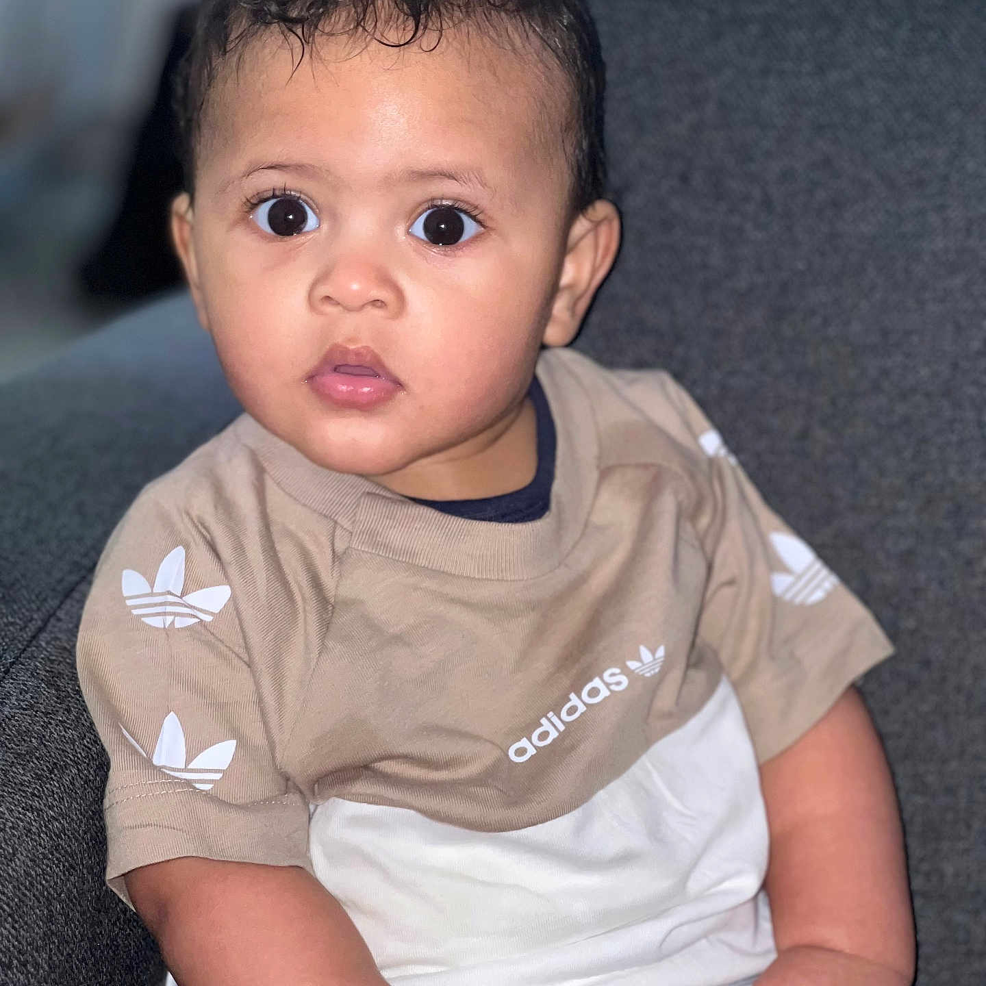 Noah Jean-Joseph a rejoint le concours — aidez-le/la à gagner de superbes lots ! adidas, casual, child, clothing, couch, curious, expression, face, furniture, hand, indoor, person, portrait, seated, shirt, short_hair, sitting, skin, toddler, young_child