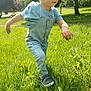 toddler, child, denim_overalls, blue_shirt, grass, outdoor, sunlight, tree, nature, walking, greenery, young_child, casual_clothing, daytime, person, footwear, playing, summer, park, exploring