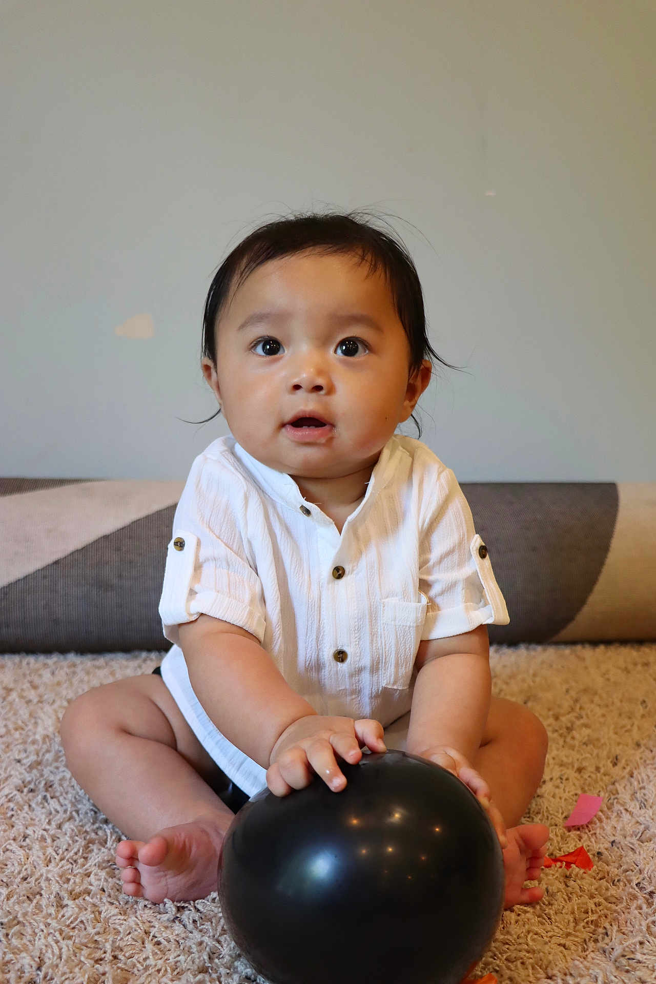 Arzen joined the competition — help win amazing prizes! baby, child, balloon, carpet, white_shirt, sitting, indoor, curious, hands, feet, face, expression, black_balloon, soft_lighting, home, floor, blanket, portrait, infant, cute