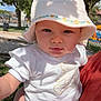 baby, blue_eyes, casual_clothing, child, cute, daylight, hat, holding, infant, leafy_tree, nature, outdoor, park, person, portrait, skin, summer, sunlight, tree, white_clothing