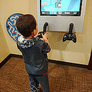 Adrian joined the competition — help win amazing prizes! child, boy, video_game, controller, gaming, indoor, carpet, wall, screen, maze_toy, clothing, spider_theme, footwear, playing, technology, entertainment, kid, game_console, standing, focus