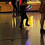 child, blurred, indoor, reflection, glowing_sticks, colorful_lights, people, legs, floor, night, party, group, shoes, dark, motion_blur, standing, casual_clothing, fun, event, celebration