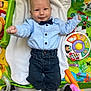 Sohan participe au concours pour gagner de l'argent avec cette photo : baby, child, blue_shirt, bow_tie, dark_pants, sneakers, play_mat, toys, smile, face, infant, lying_down, colorful, cute, happy, indoor, person, clothing, footwear, patterned_background