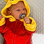 baby, pacifier, hoodie, winnie_the_pooh, red_clothing, yellow_clothing, infant, cute, soft_texture, blanket, child, face, ears, sleepwear, resting, indoors, young_child, portrait, warm_clothing, comfort