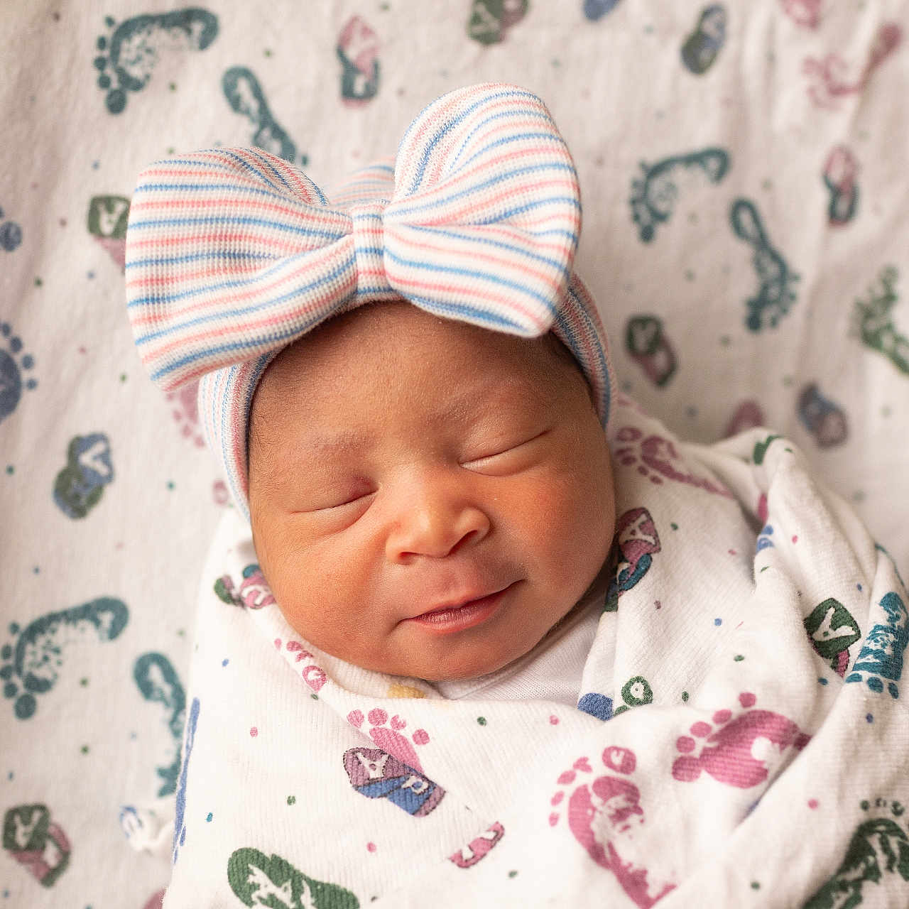 Mia is registered to the contest to win money with this photo: newborn, baby, infant, sleeping, smiling, bow, headband, blanket, footprints, crib, swaddled, cozy, cute, peaceful, indoors, child, portrait, soft_light, fabric, babycare