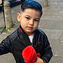 child, boy, face, hair, black_jacket, plush_toy, spiderman, toy, sidewalk, urban, street, casual, portrait, young, person, holding, outdoor, fashion, cute, confident