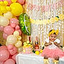 toddler, birthday_party, balloons, cake, pink_tutu, yellow_headband, table, decorations, banner, smiling_child, party, celebration, drink_straw, festive, indoor, happy, ribbons, yellow_balloons, pink_balloons, cake_toppers