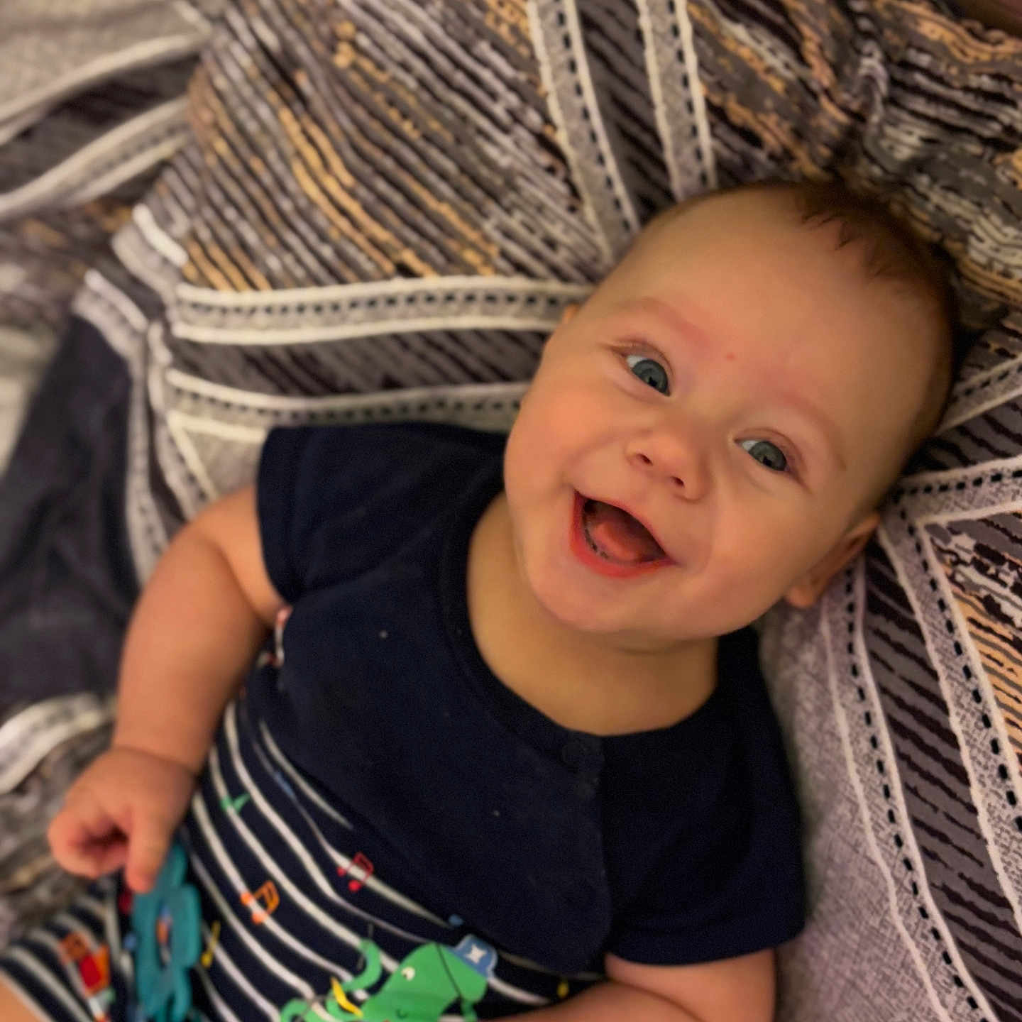 Teodor a rejoint le concours — aidez-le/la à gagner de superbes lots ! baby, blanket, child, chubby_cheeks, clothing, colorful_toy, cute, face, hand, happy, indoors, infant, lying_down, navy_shirt, patterned_blanket, playful, portrait, smiling, striped_clothing, toy