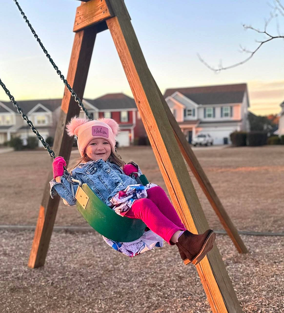Madison is registered to the contest to win money with this photo: balance, child, city, fun, grass, happy, headwear, joy, leisure, outdoor_play_equipment, person, plant, play, playground, recreation, sitting, sky, smile, soil, swing