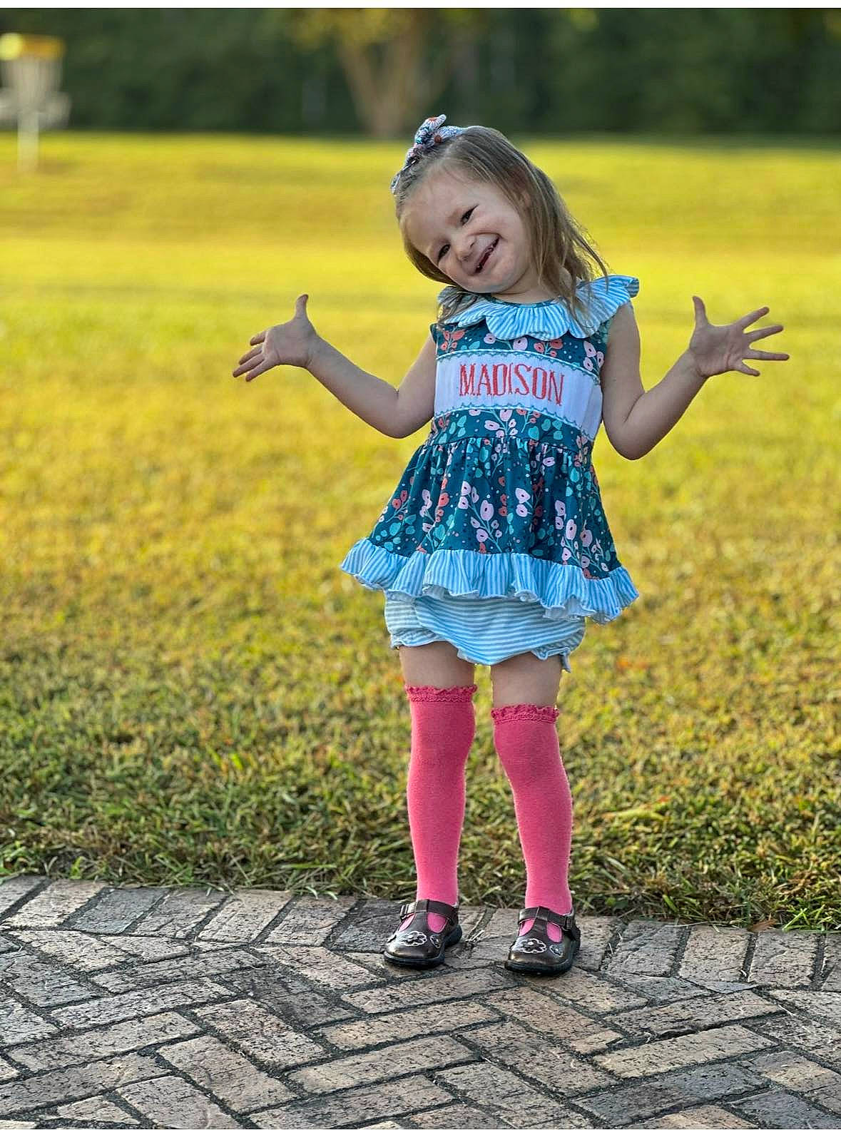 Madison is registered to the contest to win money with this photo: baby, blond, child, flash_photography, fun, gesture, grass, grassland, happy, human_leg, joy, leisure, magenta, meadow, pattern, people_in_nature, person, plant, recreation, shoe