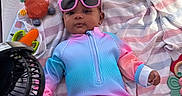 Nalani joined the competition — help win amazing prizes! baby, infant, sunglasses, colorful_clothing, blanket, playpen, toy, fan, striped_blanket, cute, relaxing, indoors, child, lying_down, summer_outfit, accessory, pink, blue, orange, diaper