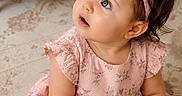 Nova joined the competition — help win amazing prizes! adorable, baby, blue_eyes, bow, carpet, child, curly_hair, cute, floral_pattern, girl, hands, headband, indoors, infant, looking_up, pink_dress, portrait, sitting, soft_light, young