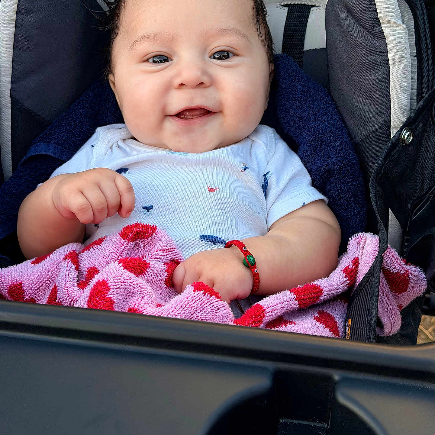 Brayan is registered to the contest to win money with this photo: baby, babywear, bracelet, child, clothing, cute, face, hair, hand, happy, infant, onesie, person, pink, portrait, red, seat, smile, stroller, towel