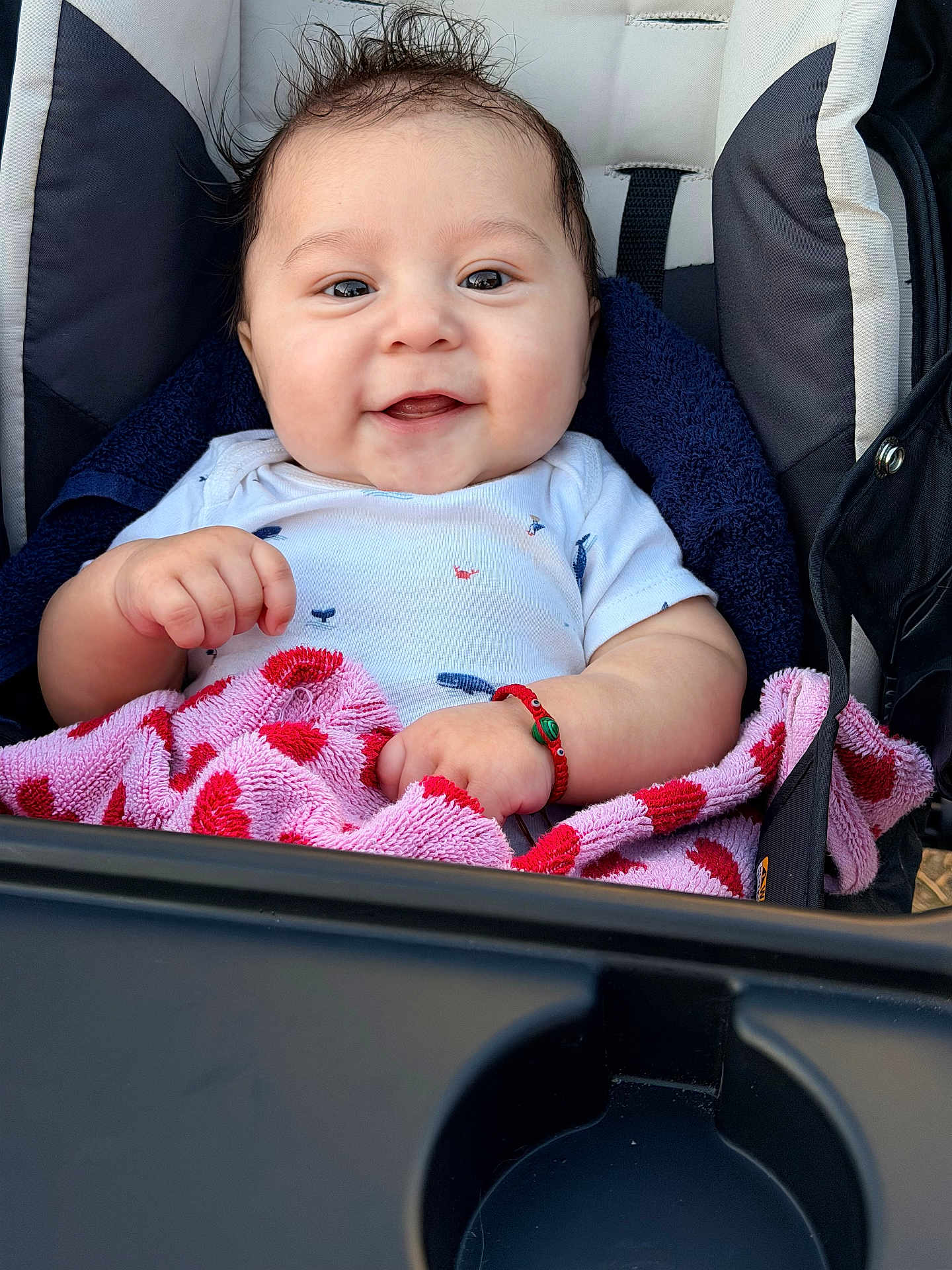 Brayan is registered to the contest to win money with this photo: baby, babywear, bracelet, child, clothing, cute, face, hair, hand, happy, infant, onesie, person, pink, portrait, red, seat, smile, stroller, towel