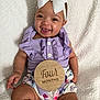 baby, infant, child, smiling, white_bow, headband, purple_outfit, ruffles, floral_bloomers, milestone_disc, four_months, blanket, chubby_legs, sitting, happy, portrait, indoor, hand, button, closeup
