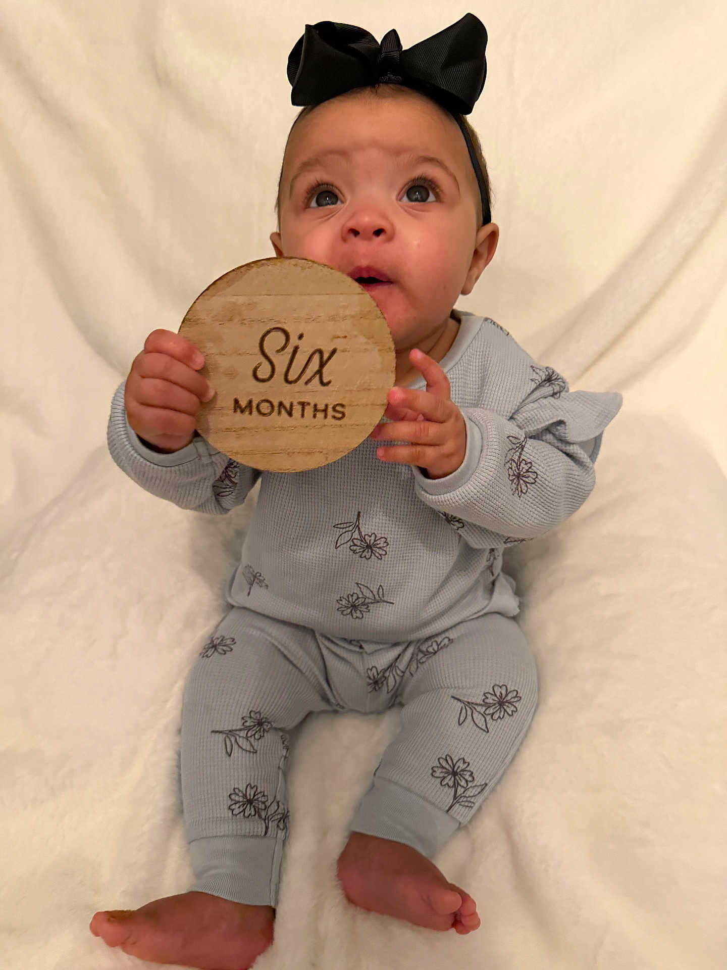 Halo joined the competition — help win amazing prizes! baby, infant, child, six_months, milestone, wooden_sign, headband, bow, pajamas, floral_pattern, blanket, sitting, portrait, looking_up, hands, bare_feet, cute, adorable, prop, studio