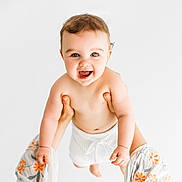 Hector joined the competition — help win amazing prizes! baby, child, smiling, happy, blue_eyes, bare_chest, white_background, adult_hands, holding, playful, cute, infant, portrait, short_hair, white_clothing, sleeves, floral_pattern, human, expression, joy