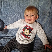 Gabin a rejoint le concours — aidez-le/la à gagner de superbes lots ! baby, child, smiling, sitting, mickey_mouse, white_sweater, blue_blanket, happy, cute, infant, portrait, clothing, soft_texture, indoor, young_child, face, person, casual, comfort, playful